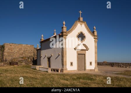 Kleine weiße Kapelle im traditionellen portugiesischen Stil an der Küste des Atlantik, neben einem Felsen. Strahlend blauen Himmel. Porto, Portugal. Stockfoto