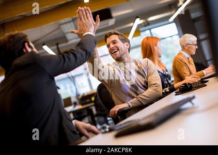 Glückliche junge schöne Unternehmer in legere Kleidung bei Business Office geben High Fives miteinander Stockfoto