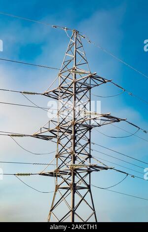 Hohe Spannung elektrische Leitung Turm vor einem blauen Himmel. Ansicht von der Seite. Stockfoto