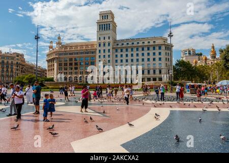 Touristen, die die Sonne genießen und die Pidgeons in der Placa de Catalunya, Barcelona, Spanien füttern. Stockfoto