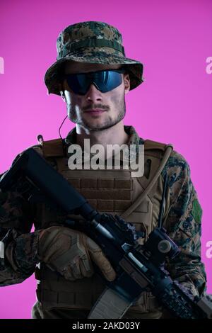 American Marine Corps Special Operations Modern Warfare Soldat mit Feuer arm Waffe und schützenden Armee taktische Ausrüstung bereit für den Kampf auf Rosa hinterg Stockfoto