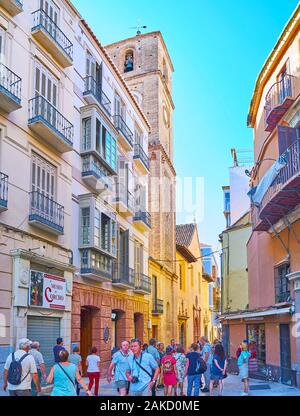 MALAGA, SPANIEN - 26. SEPTEMBER 2019: Die überfüllten Calle Granada (Straße) mit alten Bauten und hohen quadratischen Glockenturm von Santiago Apostol Kirche, auf Sep Stockfoto