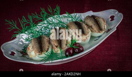 Gefüllte Eier mit Fisch auf roten Hintergrund Platte Stockfoto