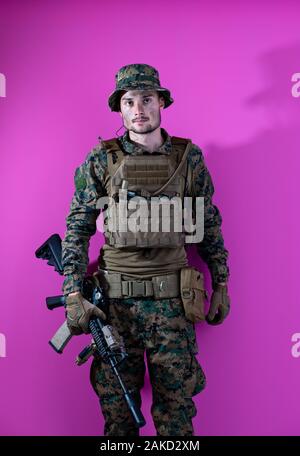 American Marine Corps Special Operations Modern Warfare Soldat mit Feuer arm Waffe und schützenden Armee taktische Ausrüstung bereit für den Kampf auf Rosa hinterg Stockfoto