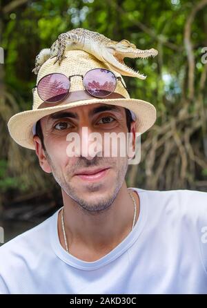 Ein Mann hält ein kleines Krokodil in seinen Händen. Selektive konzentrieren. Stockfoto