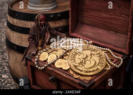 08.2018 Japan Tokyo Disney. Jack Sparrow Münzen. Künstliche Goldmünzen und eine Dekoration auf einem Holzfass. Einen gefüllten Becher mit Gold künstliche Münzen. Stockfoto