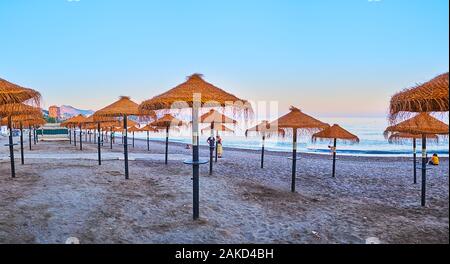 MALAGA, SPANIEN - 26. SEPTEMBER 2019: Die Zeilen von trockenen palm leaf Sonnenschirme am Strand Malagueta mit Blick auf Sonnenuntergang Himmel im Hintergrund, am 2. September Stockfoto