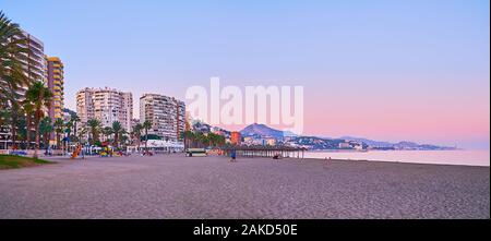 MALAGA, SPANIEN - 26. SEPTEMBER 2019: den Sonnenuntergang Panorama vom Strand Malagueta mit Berglandschaft, moderne Hochhäuser am Ufer entlang und helle purpl Stockfoto