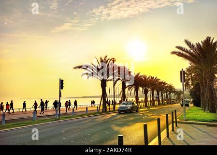 Küstenstraße entlang der Promenade des Anglais. Touristen zu Fuß und Ruhen, Sonnenuntergang in Nizza. Frankreich, Cote d'Azur Stockfoto