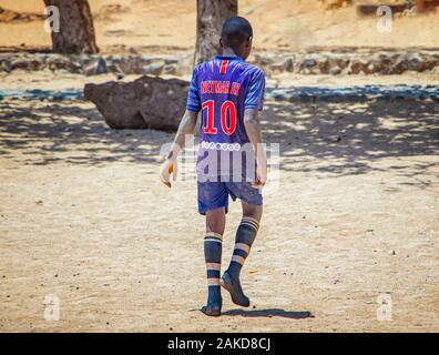 Insel Goree, Senegal - 22. April 2019: Nicht identifizierte junge Fußball spielen am Strand in der Stadt in Afrika. Der Junge trägt ein Fußball-Trikot. Stockfoto
