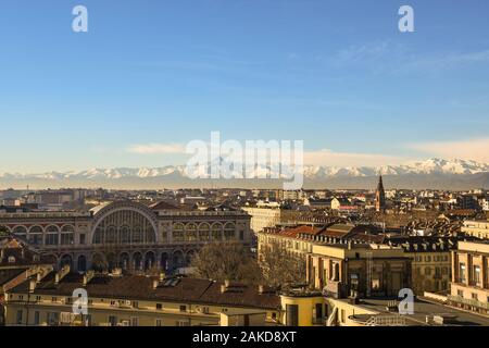 Dächer Ansicht von Turin mit dem Bahnhof Porta Nuova und die Cottischen Alpen mit Monviso peak an einem sonnigen Wintertag, Piemont, Italien Stockfoto