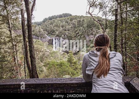 Eine junge Frau blickt auf die Hunua Falls, Neuseeland Stockfoto