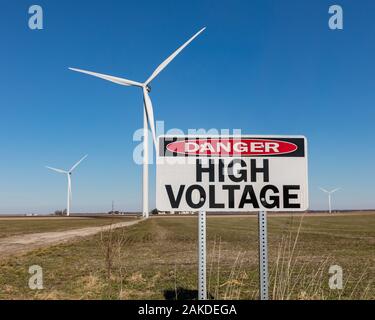 Hohe Spannung Gefahr Warnung Schild mit der Wea, Windmühle, im Hintergrund. Konzept der saubere, grüne Energie und Gefahr der Elektrizität Stockfoto