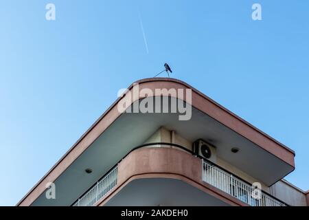Ein Bottom-up-architektonischen schießen in die Ecke eines alten Gebäudes - es ist eine Krähe auf dem Dach Stockfoto