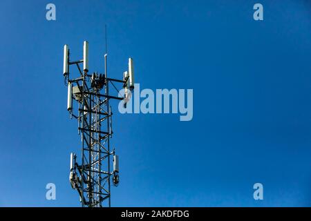 Details von mehreren Antennen auf einem stahlgitter Turm gegen einen blauen Himmel mit Kopie Raum auf der rechten Seite. Mobile Daten und Technologie Getriebe austauschen Stockfoto