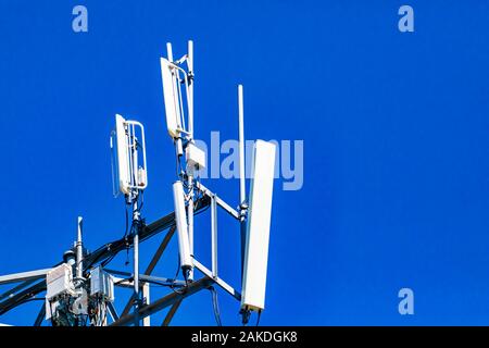 Eine Nahaufnahme und detaillierte Ansicht von elektronischen Kommunikationsgeräten auf einer Zelle Aufstellungsort Tower, mehrere weiße Antenne und RRH, Remote Radio Head, mit Kopie Raum Stockfoto