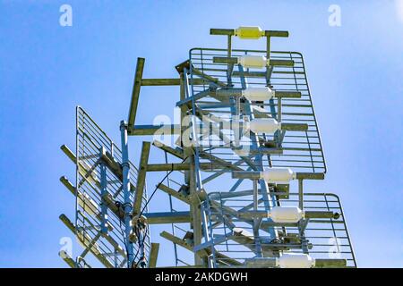 Ein niedriger Betrachtungswinkel und einer Zelle website Tower Gehäuse mit mehreren Antennen. Radio wave Signal Booster mit der stählernen Pylon gegen einen klaren blauen Himmel behoben Stockfoto