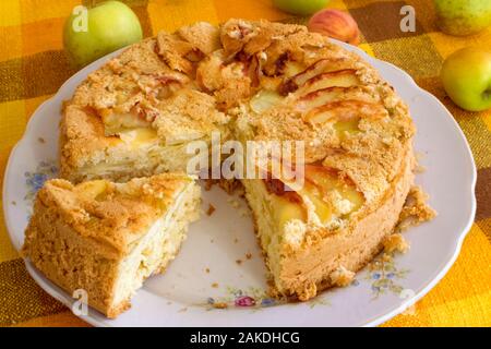 Hausgemachtes Gebäck für Tee, Apfelkuchen, Keks Teig. Schneiden Sie Kuchen mit Äpfeln auf eine Platte auf eine gelbe Tischdecke Hintergrund. Stockfoto