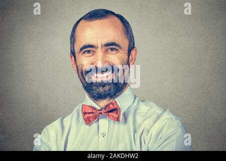 Portrait bärtiger Mann lächelnd auf sie Kamera. Happy Geschäftsmann mit eleganten weißen Hemd, Roter Schleife binden. Positiver menschlicher Emotionen. Kleidung. Single Person. Stockfoto