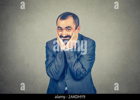 Closeup Portrait lächelnd nach eleganten bärtigen Mann in Anzug mit roter Schleife binden überrascht die Hände auf die Wangen isoliert grauen Hintergrund. Positive Stockfoto