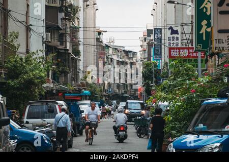 Ein paar Leute und Fahrzeuge, die ihren Weg in einer ruhigen Seitenstraße in Taipei, Taiwan Stockfoto