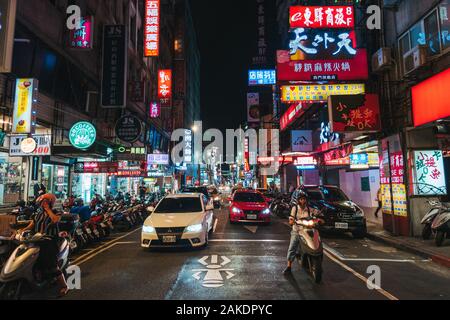 Helle, beleuchtete Schilder säumen die Straßen, während der Verkehr im Zentrum von Taipei, Taiwan, vorbei rollt Stockfoto