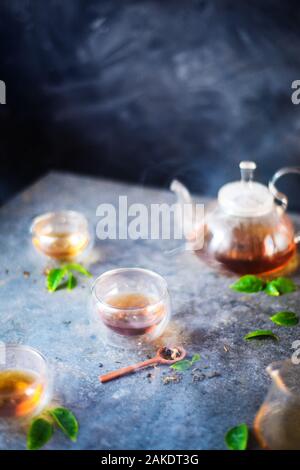 Morgen Kaffee Szene, Steintisch, Doppelwand Glas Schalen, eine Teekanne Stockfoto