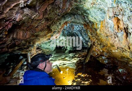 28 November 2019, Sachsen-Anhalt, Sangerhausen: Bei einem Ausflug in die wettelrode Röhrig Welle, Thomas Wäsche, Reiseführer, schaut auf bunten Sintern auf die Wände der Galerie. Da die Welle im Jahr 1885 aufgegeben wurde, der ständig fließende Wasser Mineralien aus dem Kalkstein, welche Formen eine Kruste an den Wänden gelöst. Die Farbpalette reicht von starken braunen Farbtönen Weiß, Grün, Türkis, Blau und Schwarz. Seit etwa 20 Jahren das Museum 'ErlebnisZentrum Bergbau Röhrigschacht Wettelrode' bietet hat längere Ausflüge im Untergrund in einer Tiefe von etwa 300 m. Vor kurzem wurde eine neue Tour h Stockfoto
