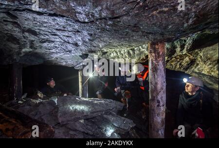 28 November 2019, Sachsen-Anhalt, Sangerhausen: Thomas Wäsche (l), Reiseführer, führt eine Exkursion durch die alten Bergbau in der wettelrode Röhrig Welle. Seit etwa 20 Jahren das Museum 'ErlebnisZentrum Bergbau Röhrigschacht Wettelrode' bietet hat längere Ausflüge im Untergrund in einer Tiefe von etwa 300 m. Vor kurzem wurde eine neue Tour gestartet wurde, in denen ein Teil der Strecke durch die Kanus abgedeckt ist. Die ersten Bergleute graben begann für Kupfererz in der Mansfelder Land etwa vor 800 Jahren. Ab dem Jahr 1750 ff., intensive Bergbau wurde durchgeführt. Insgesamt wurden rund 2,6 Mio. Stockfoto