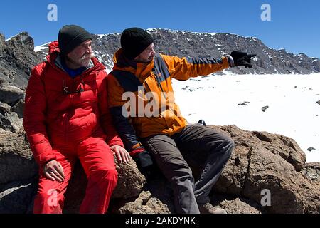 HANDOUT - 12. August 2018, Tansania, Kilimandscharo: Der Hamburger Abenteurer Achill Moser (l) sitzt neben seinem Sohn Aaron am Kilimanjaro. Achill Moser, Hamburg travel Journalist und Abenteurer, hat einen bestimmten Berg nach 28 Wüste Wanderungen genannt. Zusammen mit seinem Sohn Aaron, bestieg er den höchsten Berg in Afrika auf fast 6000 Meter. Das Abenteuer wurde in einem Dokumentarfilm und in einem Reiseführer aufgezeichnet. (Dpa' eine Hamburg Generation Reunion am Kilimanjaro") Foto: Achill und Aaron Moser/Aaron und Achill Moser/dpa - ACHTUNG: Nur für die redaktionelle Verwendung im Zusammenhang mit der aktuellen Berichterstattung und auf Stockfoto