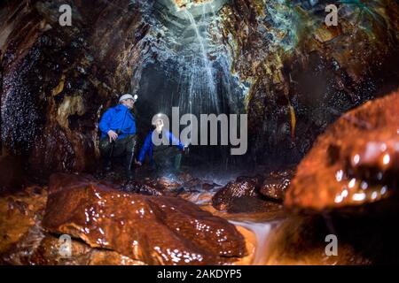 28 November 2019, Sachsen-Anhalt, Sangerhausen: Thomas Wäsche (r), Reiseführer, erklärt Maik Rüdiger auf einer Exkursion durch die wettelrode Leitung Welle wie die Sintern auf die Wände der Galerie auftritt. Da die Welle im Jahr 1885 aufgegeben wurde, der ständig fließende Wasser Mineralien aus dem Kalkstein, welche Formen eine Kruste an den Wänden gelöst. Die Farbpalette reicht von starken braunen Farbtönen Weiß, Grün, Türkis, Blau und Schwarz. Seit etwa 20 Jahren das Museum 'ErlebnisZentrum Bergbau Röhrigschacht Wettelrode' bietet hat längere Ausflüge im Untergrund in einer Tiefe von etwa 300 m. Stockfoto