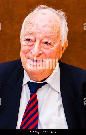 Portrait von Happy white älterer Mann mit dunkler Anzug, weißes Hemd und Krawatte gestreift blau rot Lächeln auf hellen braunen Hintergrund Stockfoto