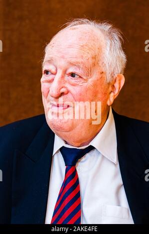 Portrait von Happy white älterer Mann mit dunkler Anzug, weißes Hemd und Krawatte gestreift blau rot Lächeln auf hellen braunen Hintergrund Stockfoto