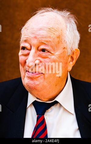 Portrait von Happy white älterer Mann mit dunkler Anzug, weißes Hemd und Krawatte gestreift blau rot Lächeln auf hellen braunen Hintergrund Stockfoto