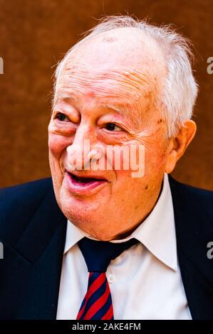 Portrait von Happy white älterer Mann mit dunkler Anzug, weißes Hemd und Krawatte gestreift blau rot Lächeln auf hellen braunen Hintergrund Stockfoto