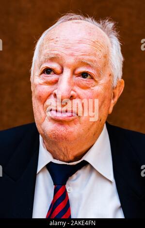 Portrait von Weißen älteren Mann mit dunkler Anzug, weißes Hemd und Krawatte gestreift blau rot bis auf hellen braunen Hintergrund Stockfoto