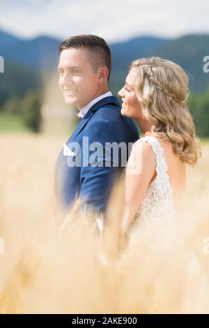 Brautpaar zärtlich umarmen in Weizen Feld irgendwo in der slowenischen Landschaft. Kaukasische gerne romantische junge Paar ihre Hochzeit feiern. Stockfoto