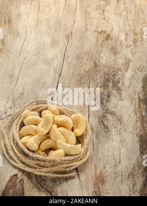 Viele Cashewkerne mit Garn im Alter von Holz. Nahaufnahme Stockfoto