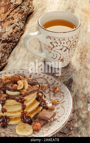 Stapel von heißen Pfannkuchen mit Nüssen, Bananen und Schokolade Sirup. Nahaufnahme Stockfoto