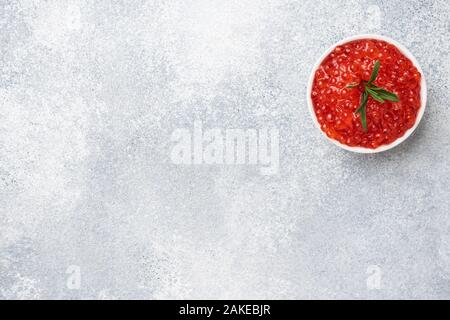 Roter Lachskaviar in eine Platte auf grauem Beton Hintergrund. Snack Delikatesse. Platz kopieren Stockfoto