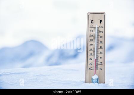 Thermometer auf den Bergen im Schnee zeigt Temperaturen unter Null. Niedrige Temperaturen in Grad Celsius und Grad Fahrenheit Stockfoto