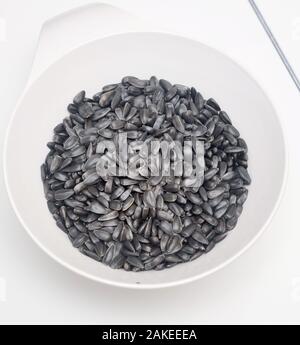 Schwarze Sonnenblumenkerne in eine Schüssel geben. Stockfoto