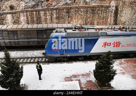 (200109) - BAOJI, Januar 9, 2020 (Xinhua) - Assistent Officer on Duty Zhao Shuai begrüßt den Personenzug mit einem Güterzug auf der Seite bei Qingshiya Bahnhof in Baoji Stadt, in der Provinz Shaanxi im Nordwesten Chinas, dem 7. Januar 2020. Qingshiya Bahnhof ist an der Spitze der Qinling Mountains auf Chinas erste elektrifizierte Eisenbahn, Baoji - Chengdu Eisenbahn. Von steilen Klippen umgeben, die 'Cloud' besteht aus nur zwei Titel und dient als einen kurzen Stop für die vorbeifahrenden Züge auf der Bahn. Klein, wie er ist, die Station hat alle die lebenswichtigen Organe. Für den Betrieb der Bahn st Garantie Stockfoto