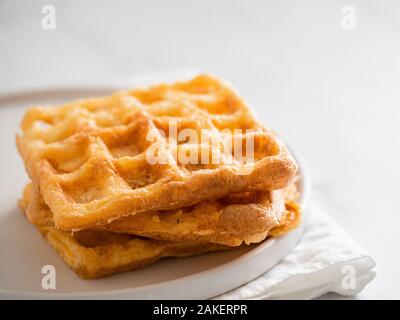 Perfekte herzhaften keto Waffeln. Zwei Zutaten chaffles auf die Platte über der weißen Marmor Hintergrund. Eier und Parmesan low carb Waffeln. Stockfoto