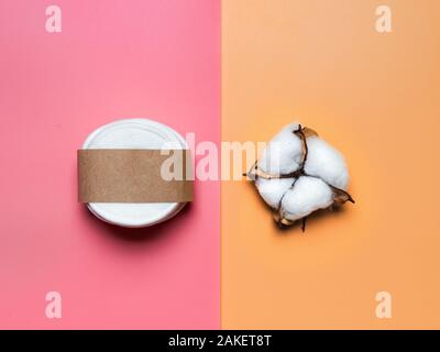 Wiederverwendbare Wattepads und Baumwolle Blume auf bunten rosa und gelben Hintergrund. Minimalistisches Konzept für Ökologie, Wiederverwendung Textil, Kosmetik Industrie, null Abfall. Top View oder flach. Bunten Hintergrund Stockfoto