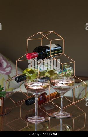 Wein Flaschen in einem Rack mit Weingläsern auf einem Glastisch Stockfoto