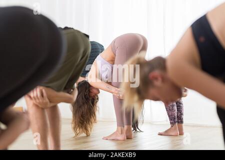Gruppe von jungen sportlich attraktive Frauen im Yoga Studio, Yoga Unterricht mit Kursleiter, stehend, Stretching und Entspannung nach dem Training Stockfoto