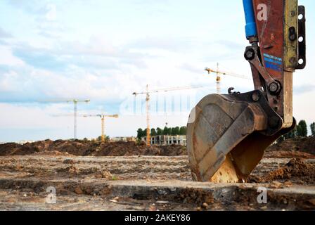 Bagger Schaufel auf der Baustelle bei Sonnenuntergang Hintergrund und auf den blauen Himmel. Flurbereinigung, Sortierung, Pool, Aushub, Grabenaushub, utilit Stockfoto