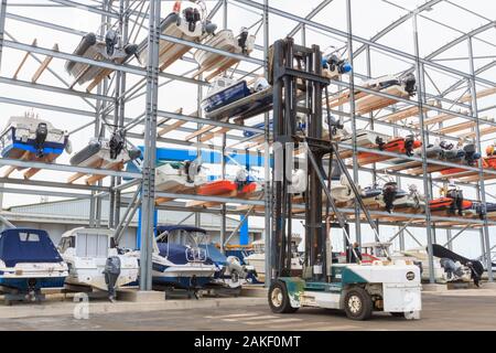 Heavy lift Gabelstapler laden kleine Sportboote im Rack. Stockfoto