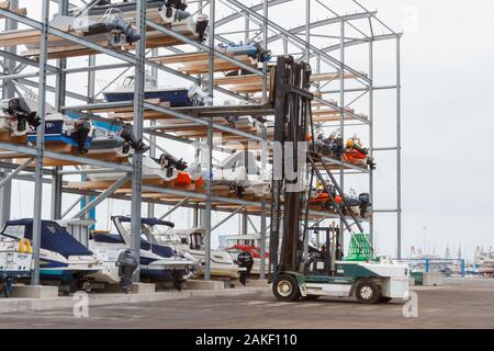 Heavy lift Gabelstapler laden kleine Sportboote im Rack. Stockfoto